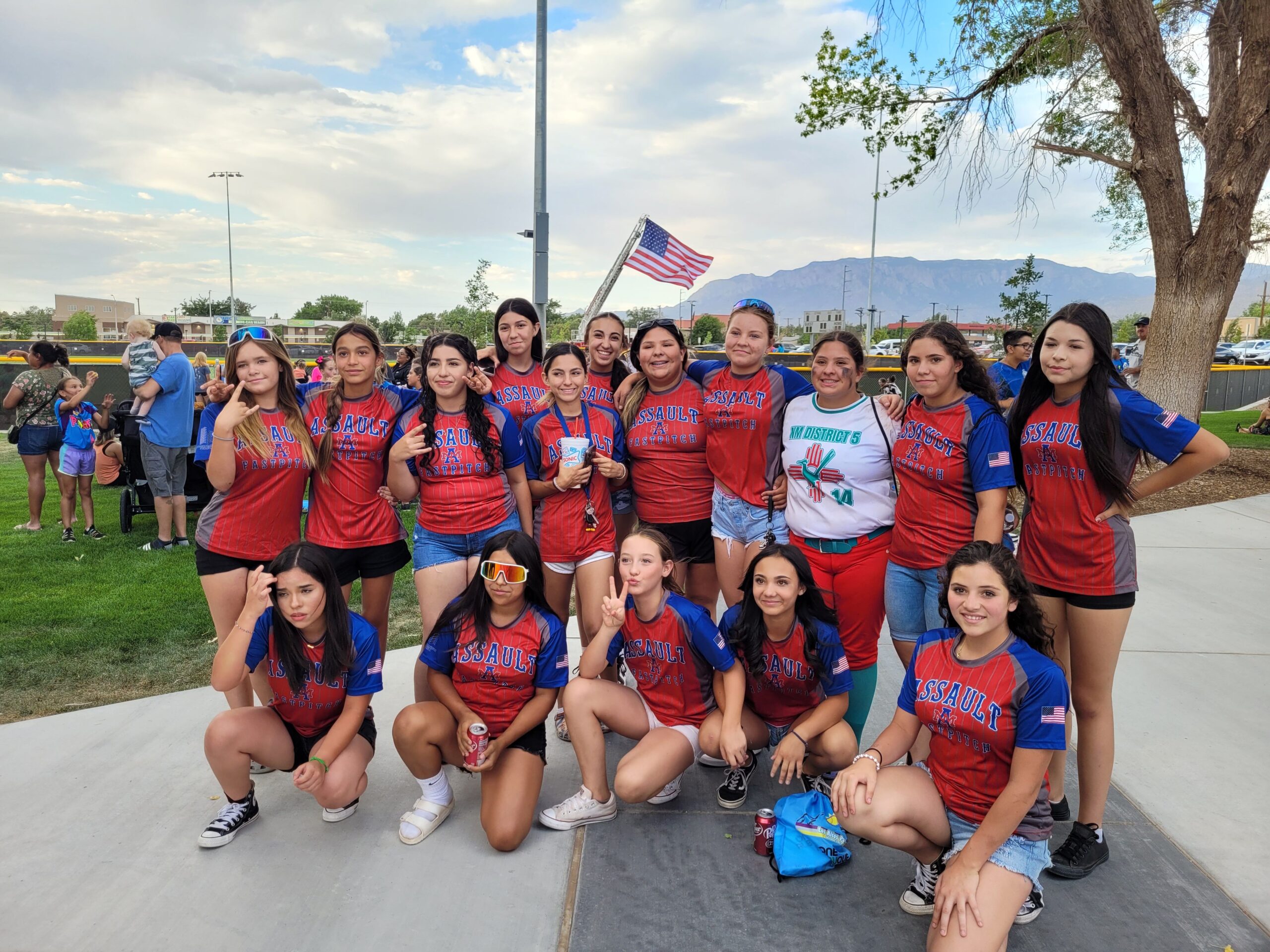 A Positive Trajectory Foundation and Assault Fastpitch athletes gathered outdoors in red and blue uniforms